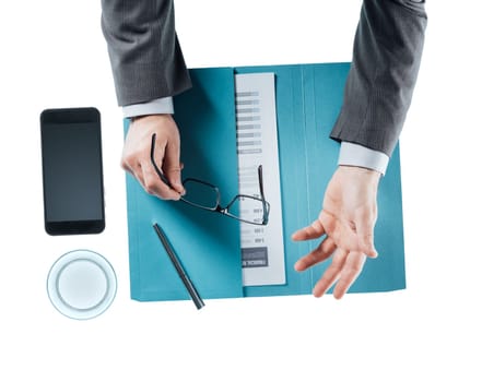 Businessman at desk holding glasses and gesturing while discussing during a meeting, hands close up