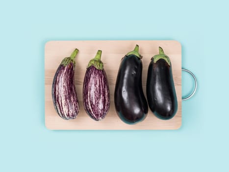 Fresh eggplants on a wooden chopping board, food preparation and healthy eating concept