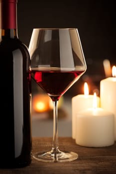 Red wine glass and bottle close up with restaurant on background.
