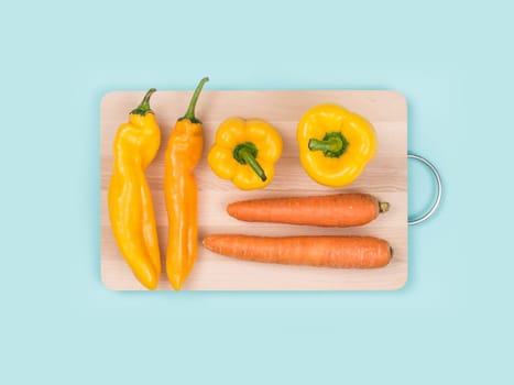 Fresh carrots and peppers on a wooden chopping board, cooking and healthy eating concept