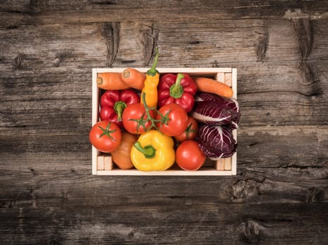 Fresh tasty red and yellow vegetables in wooden crates on a rustic wooden table