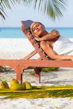 Young blonde girl sunbathing on sunbeds