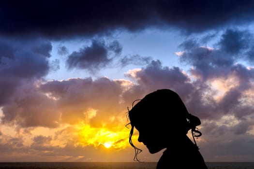 Silhouette of a young girl with dramatic sunrise over the ocean in background - Los Cocoteros, Lanzarote, Canary Islands, Spain