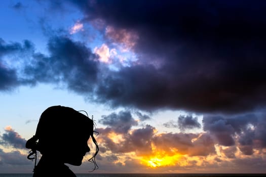 Silhouette of a young girl with dramatic sunrise over the ocean in background - Los Cocoteros, Lanzarote, Canary Islands, Spain