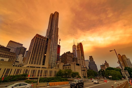 Brooklyn Bridge, New York, United States - June 08, 2015: People walk and while other tourists observe, from the bridge, the Manhattan skyline.