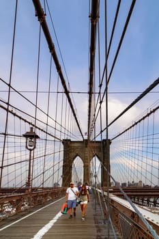 Brooklyn Bridge, New York, United States - June 08, 2015: People walk and while other tourists observe, from the bridge, the Manhattan skyline.