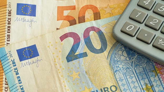 Euro banknotes and calculators are on a table
