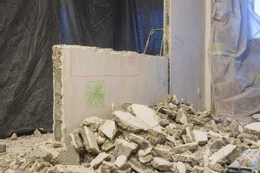 Broken pieces of the wall lie near the wall being dismantled