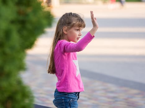 Six-year-old girl waving his hand, side view