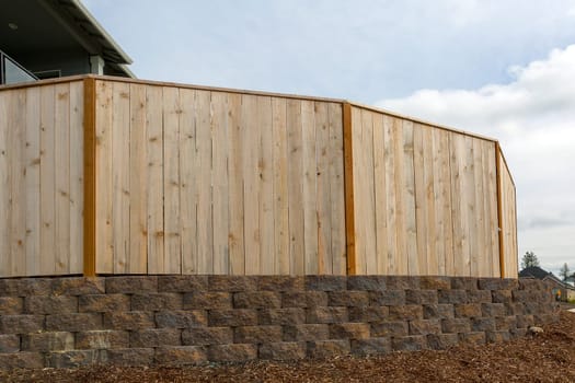 New house backyard wood fence stone wall and landscaping garden barkdust mulch