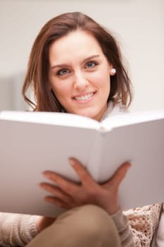 beautiful fascinating woman reading a book in her living room on a white sofa