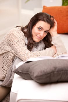 girl reading a book on her living room on a sofa