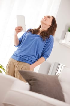 a self confident successful woman smiling in her living room reading stock options information in her tablet