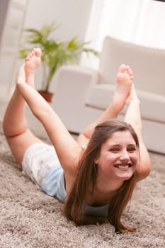 girl holding a strange position staying on the belly and taking her feet with her hands ... but she's laughing!