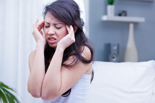 beautiful girl has a painful headache in her living room and wants immediately a painkiller