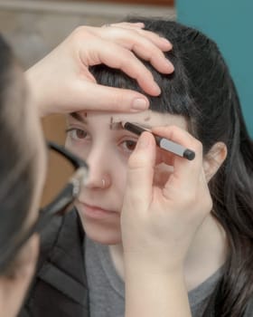 Permanent makeup. Verification of proportions. Cosmetologist applying permanent make up on eyebrows- eyebrow tattoo
