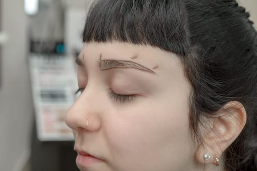 Permanent makeup. Verification of proportions. Cosmetologist applying permanent make up on eyebrows- eyebrow tattoo