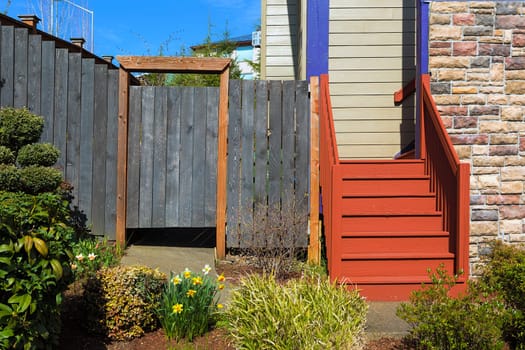 Home garden frontyard with plants wood fence gate colorful staircase sidings and stone wall