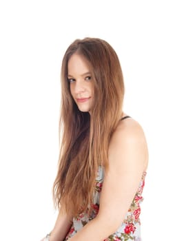 A beautiful young woman sitting for a portrait image in a colorful.dress and long brunette hair, isolated for white background.