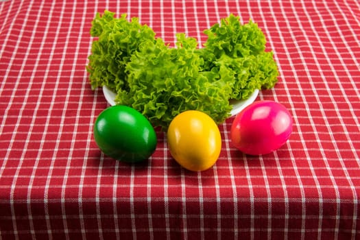 Easter eggs and fresh green salad on red white checkered tablecloth. Health concept.