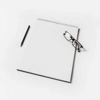 Album, glasses and pencil on white paper background. Blank sketchbook and stationery.