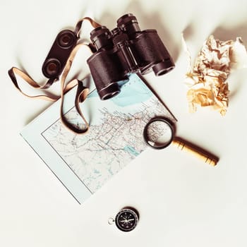 Travel still life. Map, binoculars, compass, magnifier and crumpled paper. Vintage toned image. Top view. Flat lay.