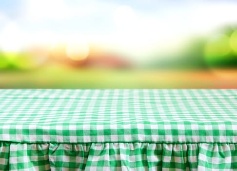 Checkered gingham picnic tablecloth blurred nature background.Empty space food advertisement template.