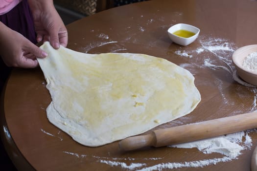 Woman making dough with meat at home on the kitchen table