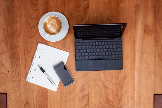 notebook,smartphone, notepad with pen and  cappuccino on wooden table from above