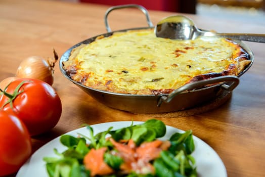 baked quiche with field salad on wooden table