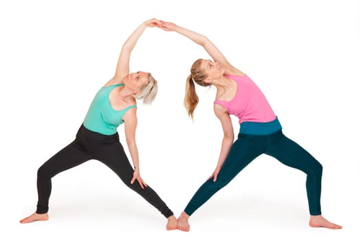 Full-body view of two young blonde women during a partner yoga exercise standing against a white background with slight shadows.