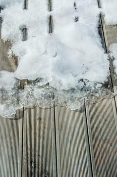 Melting snow on a wooden terrace, close-up