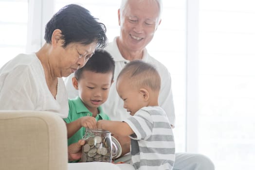 Asian elderly and children saving money at home. Family financial planning, investment, insurance, retirement, senior and junior banking concept.