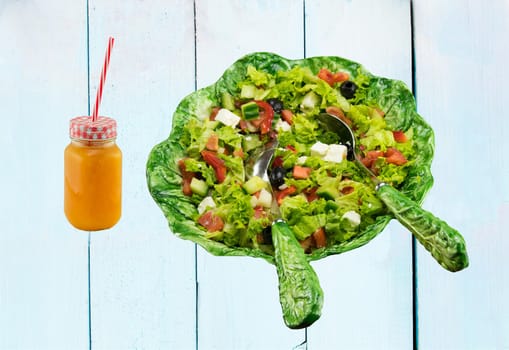 Healthy fresh vegetable salad in ceramic salad bowl and an glass filled with fresh pressed orange juice. Spring salad. health concept.