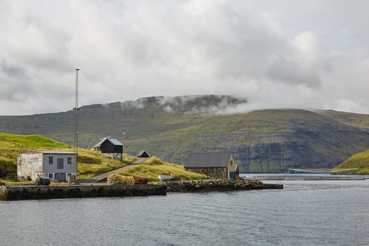Village in wild and beautiful coastal landscape of Faroe Islands, Denmark.
