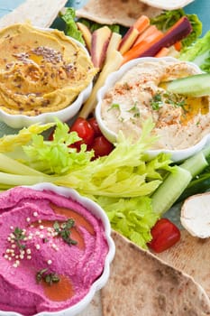 Different varieties of hummus with fresh vegetables