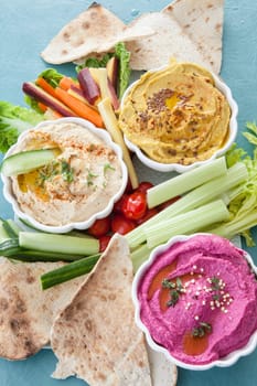 Different varieties of hummus with fresh vegetables
