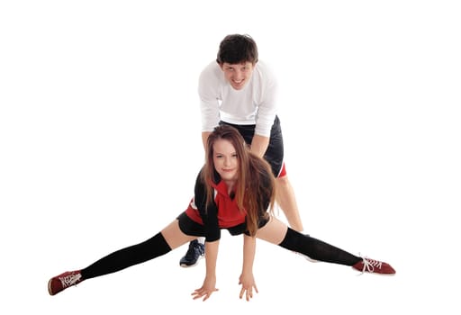 A young couple in sports outfits, the woman making spargate on the.floor, the man holding her from behind, isolated for white background.