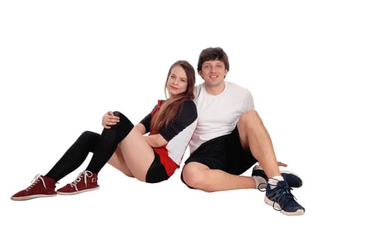 A beautiful young couple sitting on the floor in sports attire relaxing.after exercising, isolated for white background.
