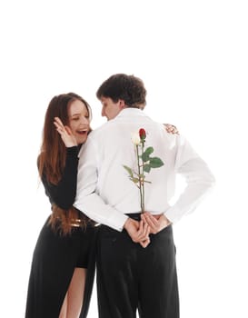 A happy young couple standing isolated for white background, he has.some roses for her to surprises his girlfriend.