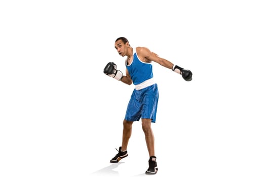Sporty man during boxing exercises. Photo of boxer on isolated on white background. Strength, attack and motion concept. Fit african american model in movement. Afro muscular athlete in sport uniform