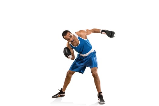 Sporty man during boxing exercises. Photo of boxer on isolated on white background. Strength, attack and motion concept. Fit african american model in movement. Afro muscular athlete in sport uniform