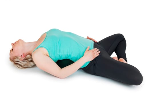 Full-body view of a young blonde woman during the yoga exercises Cross-legged sitting in a supine position against a white background with a slight shadow.