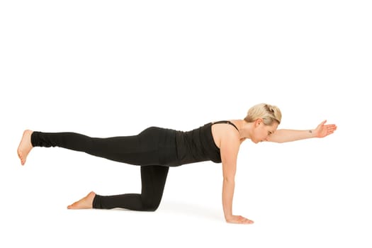 Lateral full-body view of a young woman against a white background showing the yoga exercise diagonal cat (Majariasana).