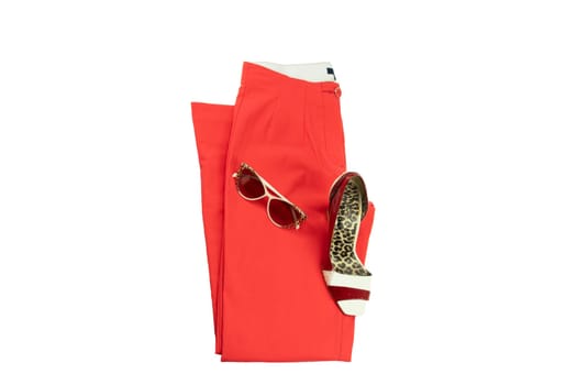 Red elegant woman trousers, an matching elegant female shoe and a fashionable sunglasses  on it.  Fashion concept. Isolated on white.