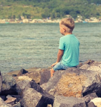 Cute caucasian boy at seaside. Rear view. Leisure time