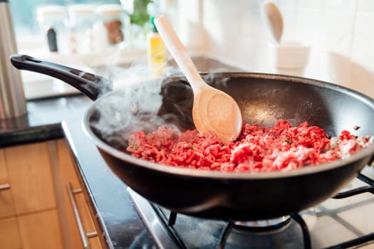 Beef mince and onions browning off in a wok on a home cooker.