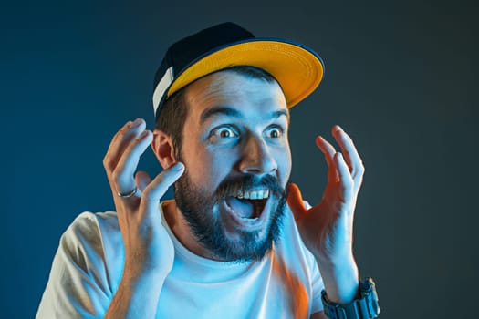 The anger and screaming man. Hate, rage. Crying emotional angry man in colorful bright lights at studio background. Emotional face. Fan human emotions, facial expression concept.