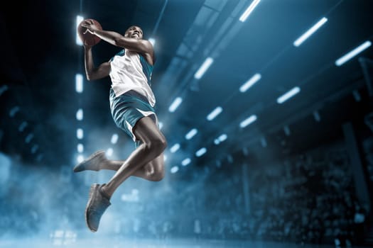 Basketball player in motion or movement on big professional arena during the game. Player making slam dunk. unbranded uniform. attack and decisive blow concept. professorial afro american athlete