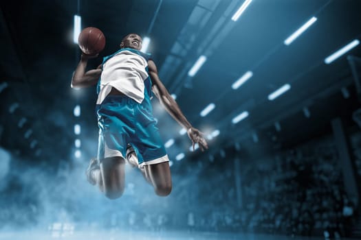 Basketball player in motion or movement on big professional arena during the game. Player making slam dunk. unbranded uniform. attack and decisive blow concept. professorial afro american athlete